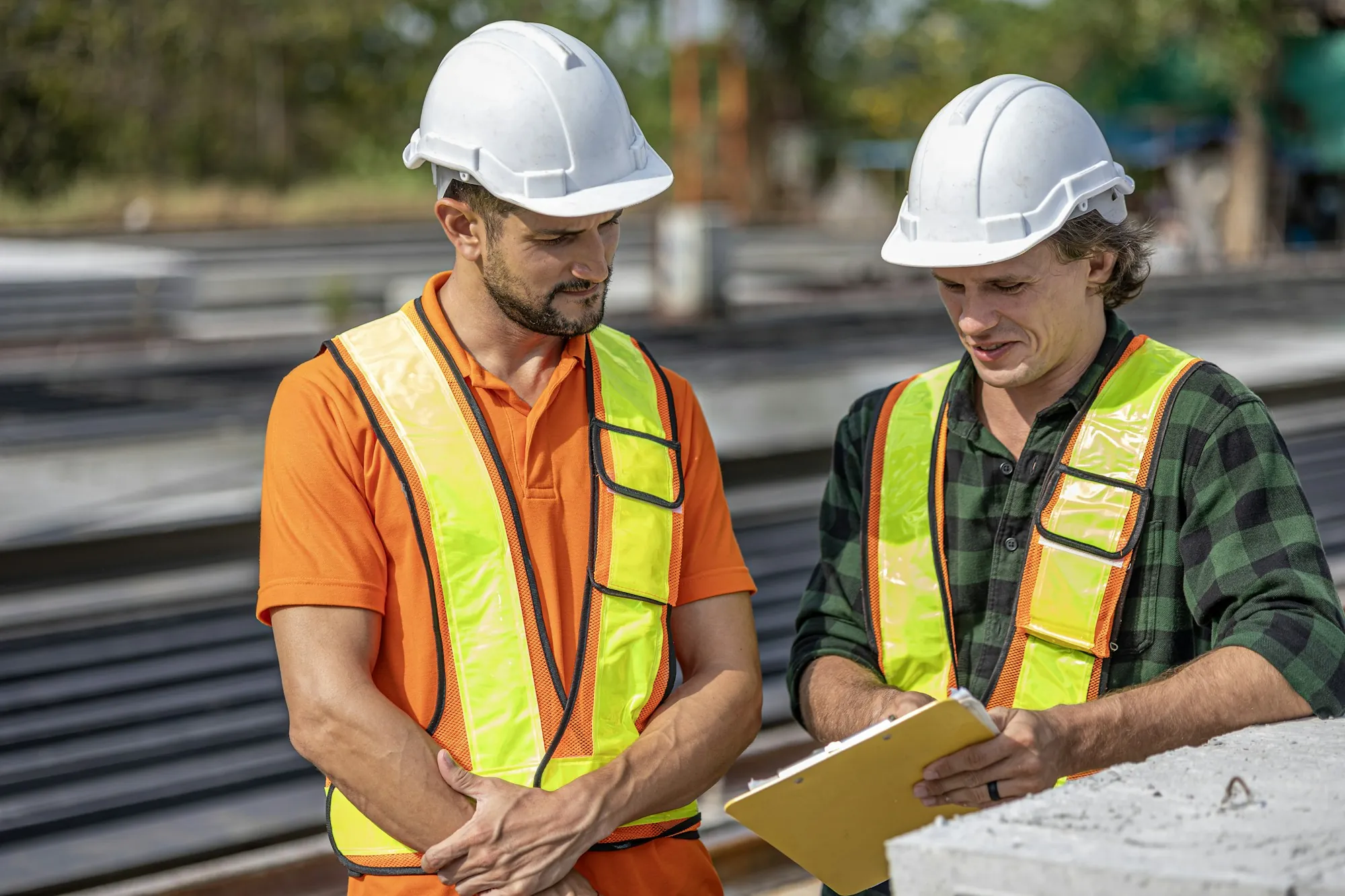 Two tradespeople in hard hats reviewing job paperwork on site