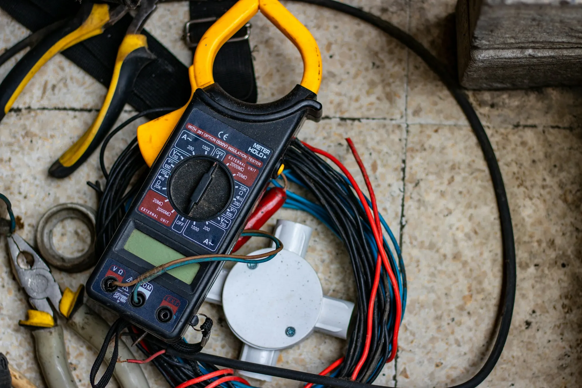 Clamp meter and hand tools laid out on a work surface