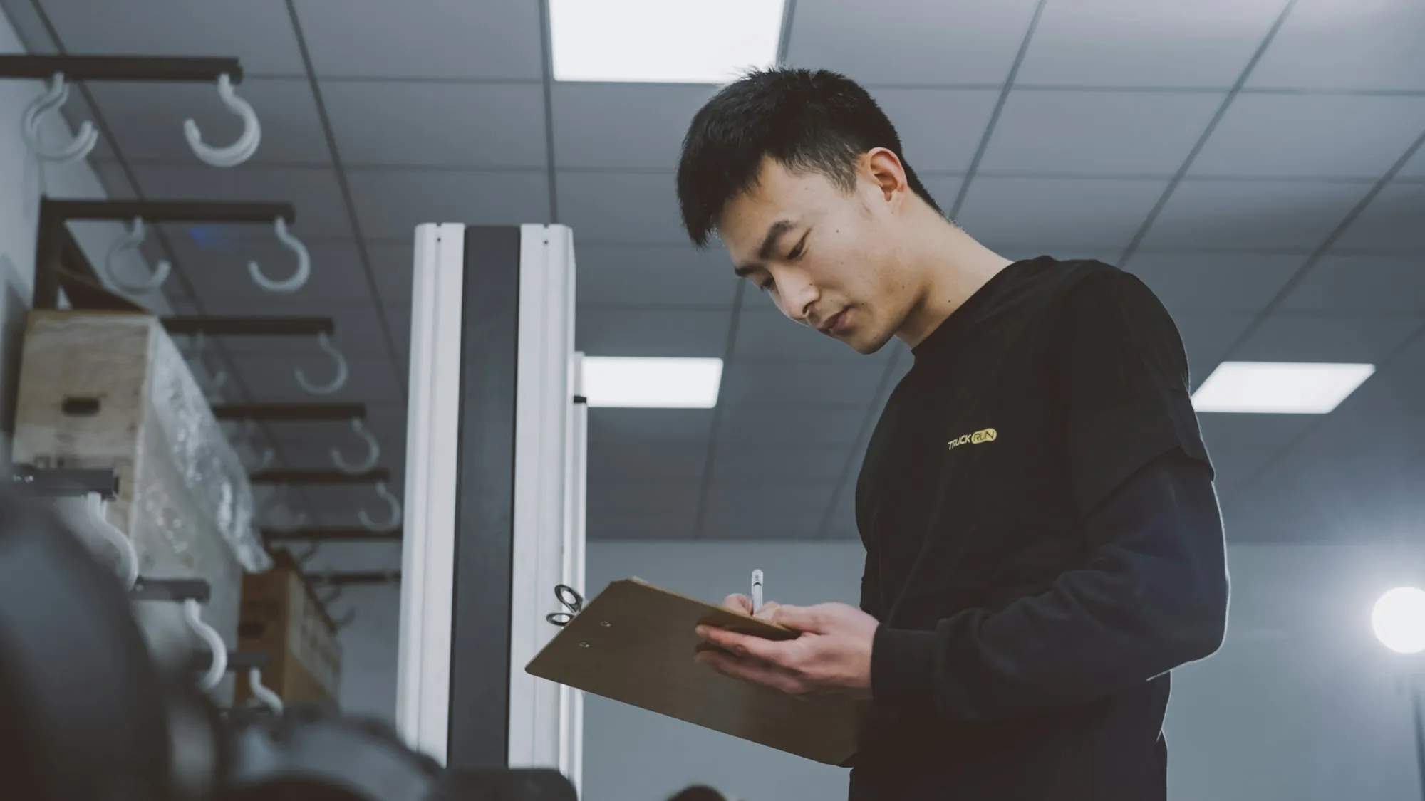 Electrician standing in a work area reviewing a job list on a clipboard