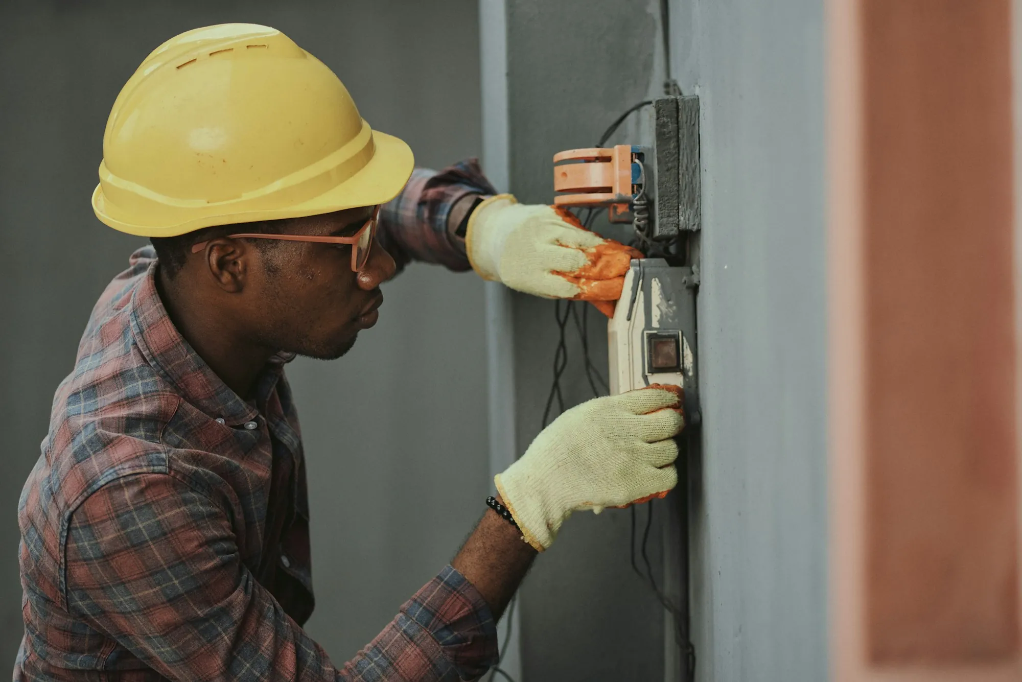 Electrician in a hard hat running new wiring inside a home