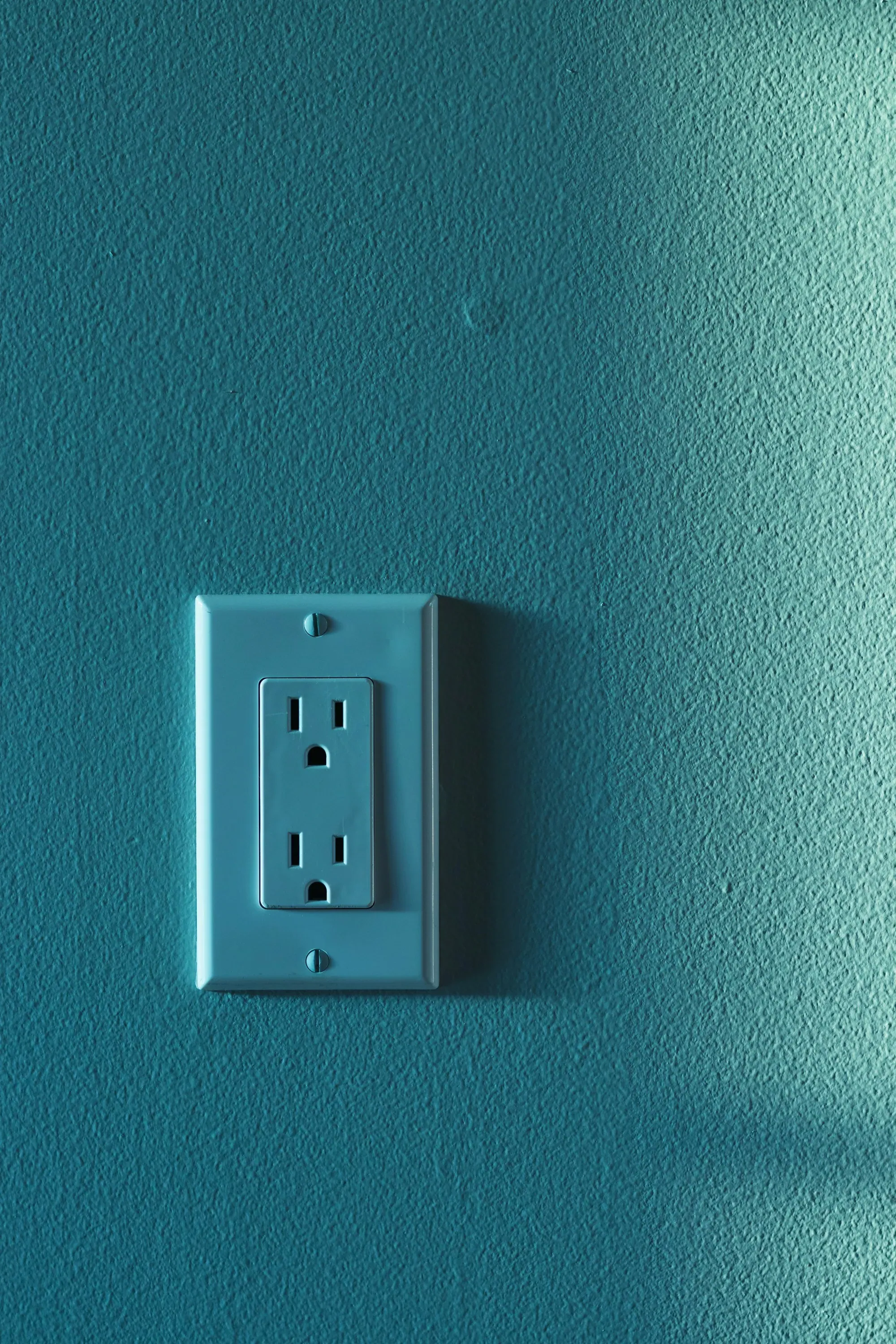 Wall-mounted electrical socket on a plain painted interior wall