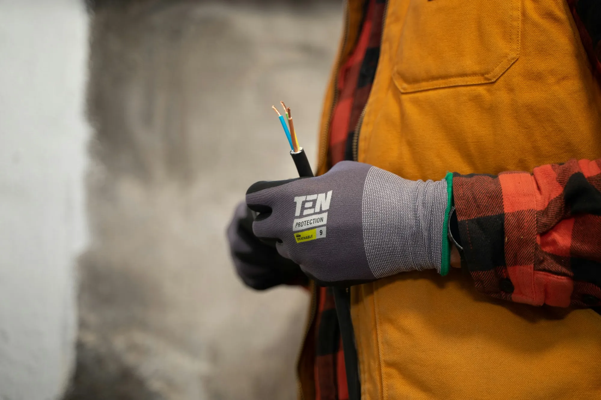 Electrician's gloved hands holding stripped conductors ready to terminate